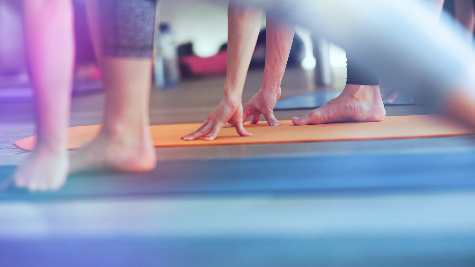 Nahaufnahme F\u00fc\u00dfe und H\u00e4nde auf oranger Yogamatte