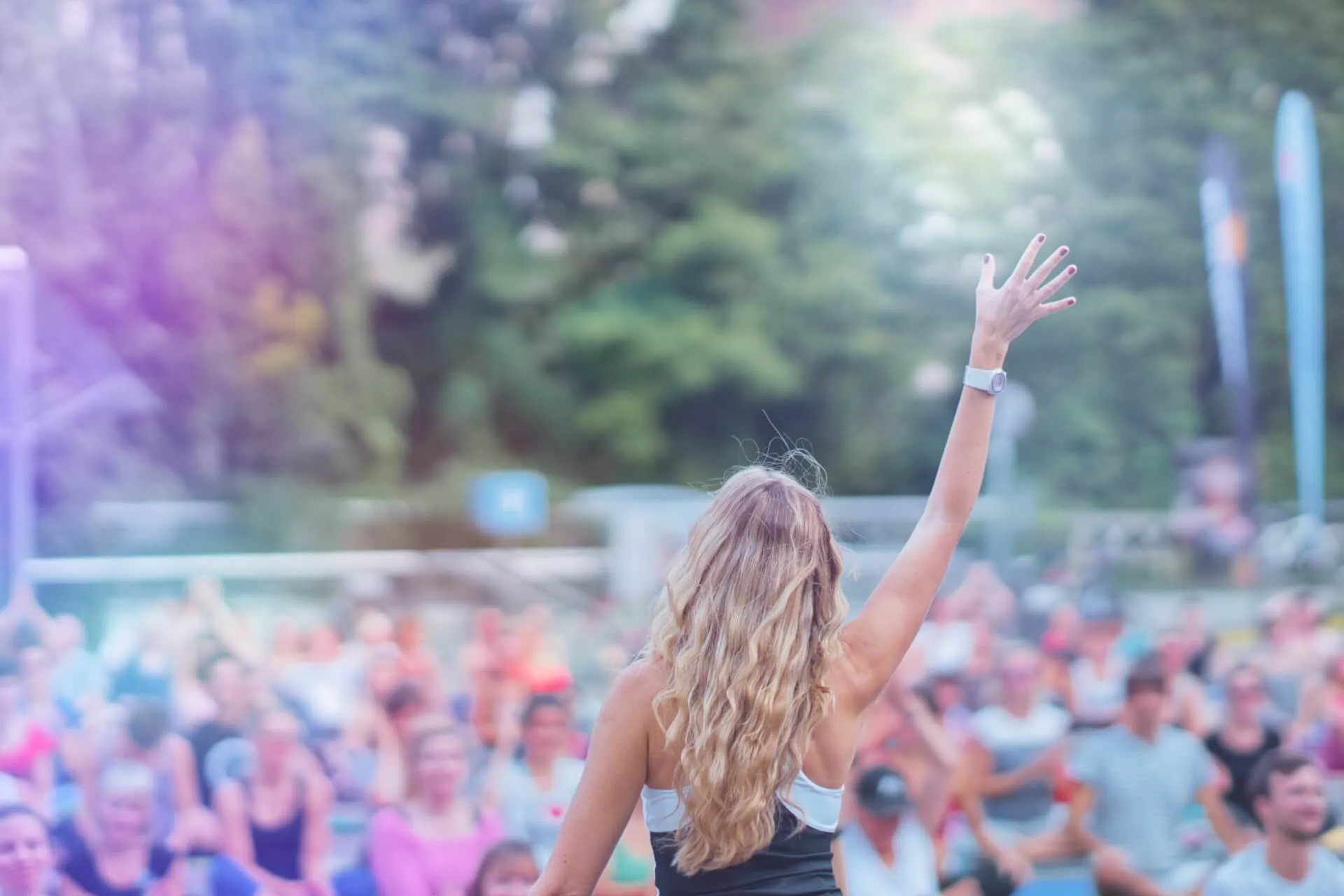 Suzanne Freiherz von hinten, Hand erhoben, vor einer riesigen Outdoor-Gruppe im Park
