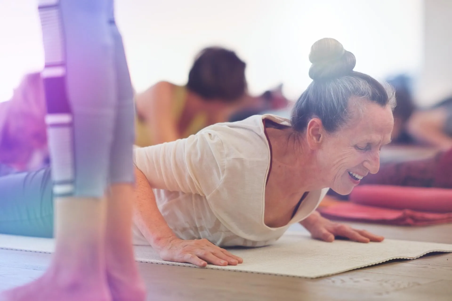 Aeltere Frau laechelt strahlend im Plank, helles Studio