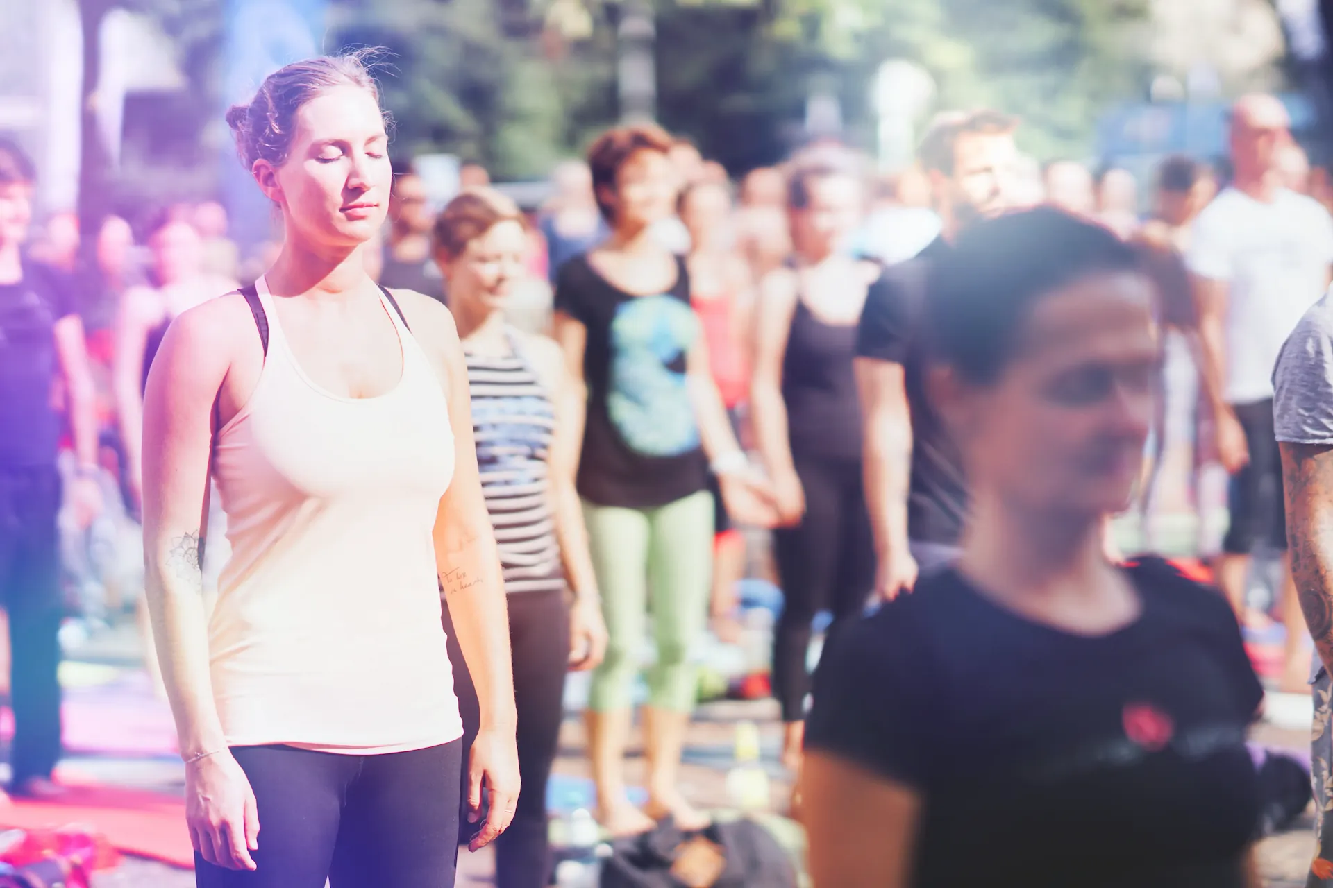 Frau mit geschlossenen Augen stehend in Meditation, Menge dahinter
